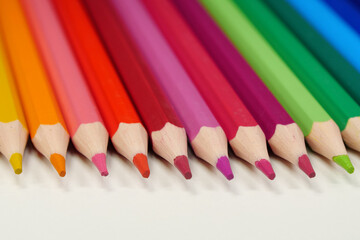 New wooden colored pencils of rainbow colors, perfectly sharpened, lie on table
