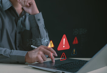 Cybersecurity warning concept showing professional analyzing digital alert icons on laptop, representing system risk, data threats, security notifications, and IT protection awareness.