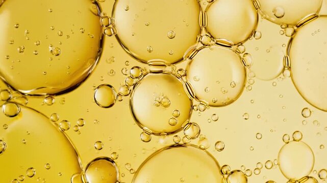 Mesmerizing close-up of golden oil bubbles in liquid, forming a vibrant and dynamic abstract pattern, ideal for backgrounds and scientific concepts related to fluid dynamics and emulsions