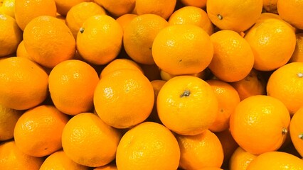 Fresh ripe oranges stacked closely together, showcasing vibrant orange color and smooth citrus...