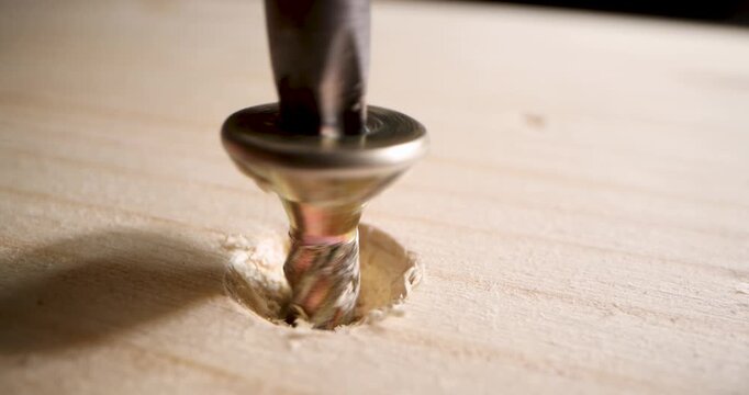 closeup of screwing a wood screw into a wooden board with screwdriver. carpenter's workshop