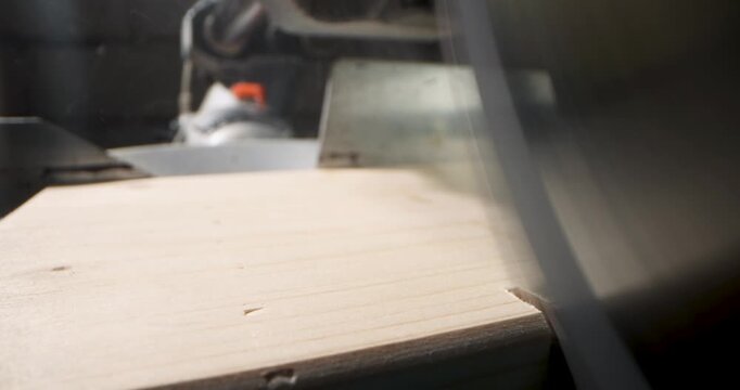 closeup of cutting wooden plank with miter saw