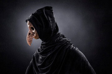 Creepy figure with animal bird skull over dark misty background