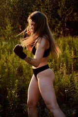 Young woman in black underwear standing in a rainy field