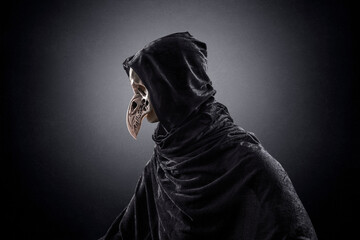 Creepy figure with animal bird skull over dark misty background