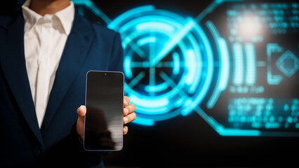A business professional woman in a dark blue suit uses a smartphone in front of glowing digital dashboards, highlighting data analytics, technology integration, modern in futuristic workspace.