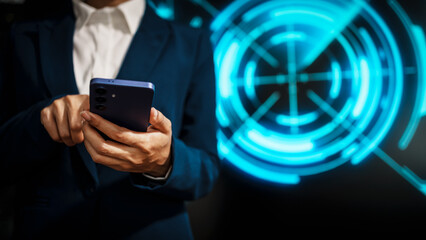 A business professional woman in a dark blue suit uses a smartphone in front of glowing digital dashboards, highlighting data analytics, technology integration, modern in futuristic workspace.