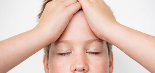 Close-up portrait teenage boy touching head with pain, suffering from headache or concussion,...
