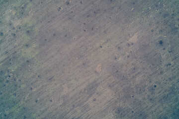 Aerial top down view of agricultural field heavily scarred by numerous shell craters. War zone bombardment aftermath and rough earth texture.