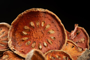 Pile of dried Bael fruit slices on black background. Close-up shot