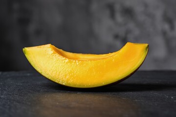 Single ripe mango slice with glistening orange flesh and a curved glossy peel