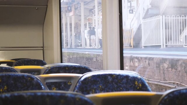 POV arriving to a train station with light shining through and can see outside through the window. Video of inside the train carriage. Sydney public transport.