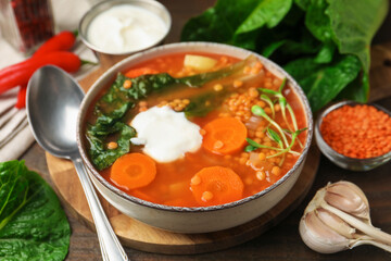 Tasty lentil soup served on wooden table, closeup