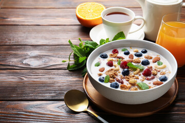 Healthy breakfast. Oatmeal with nuts, berries and milk in bowl on wooden table, closeup. Space for text