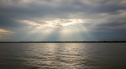 Sunbeams breaking through dramatic clouds over a calm lake