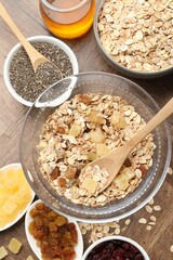 Making granola. Flat lay composition with oat flakes, dried fruits, chia seeds and honey on wooden table