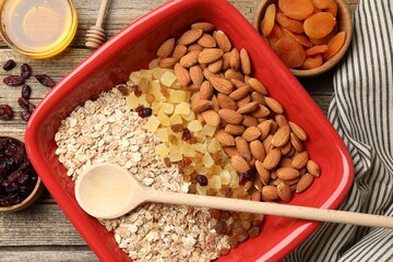 Making granola. Oat flakes, dried fruits, almond nuts and honey on wooden table, flat lay