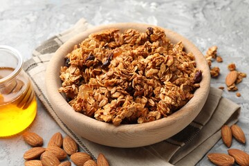 Tasty granola with dried fruits and honey on light grey table, closeup