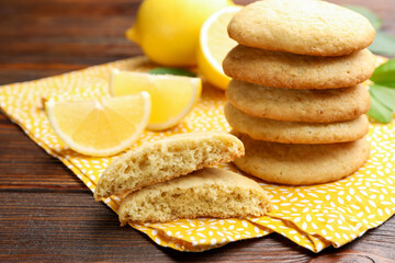 Tasty lemon cookies and fruit slices on wooden table, closeup