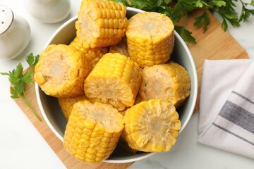 Pieces of tasty corn cobs and parsley on white table, flat lay