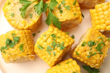 Pieces of boiled corncobs with parsley on plate, top view