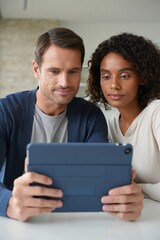 Man and woman examining a tablet together with focused, collaborative expressions