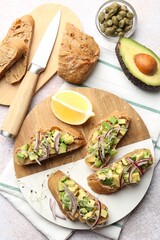 Delicious bruschettas with avocado, onion and microgreens served on light table, flat lay
