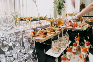 Staff wearing gloves serve a buffet table with tartlets as appetizers.