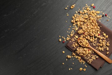 Tasty granola with dried fruits and spoon on black table, top view. Space for text