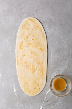 Overhead view of oil and flour mixture spread on raw chinese scallion pancakes dough, top view of homemade scallion pancakes, process of making cong you bing