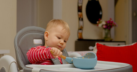 Boy explores the joys of self-feeding during breakfast at home. His concentration and excitement shine through as he enjoys his meal with a spoon.