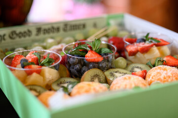 Assorted fresh fruits and berries in portioned cups with mint
