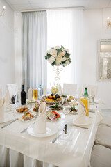 A banquet table set for guests with food, fruits and flowers.