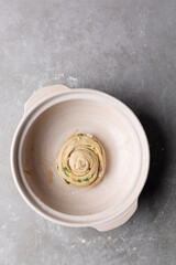 overhead view of shaped raw scallion pancakes in a donabe, top view of shaped scallion pancake dough