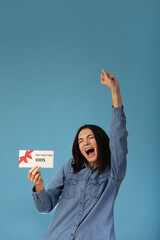 Young excited woman wear pajamas jam sleep eye mask rest relaxing at home point index finger on gift voucher flyer mock up isolated on pastel blue background studio. Good mood night bedtime concept