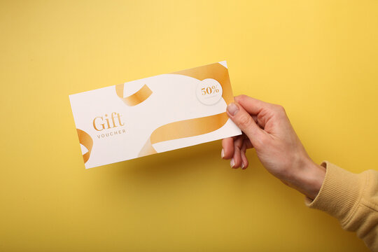 Top view of woman holding gift voucher lettering on white background