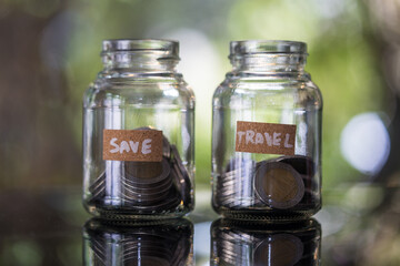 A glass jar filled with coins labeled save and travel, a symbolizing financial management and the importance of saving money.
