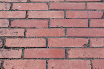 Close-up texture background of a well-maintained, vintage red brick pavement pathway in a park or garden, showing the repeating pattern and rough, durable surface detail. Copy space.