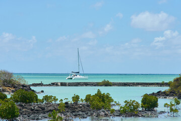 A scenic caramaran boat cruises across clear tropical ocean waters, showcasing vibrant turquoise tones and a peaceful island atmosphere. The image captures a sense of adventure, freedom and paradise