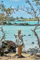 A beautiful woman enjoys spending time on the coastline with a scenic view of a tropical island in Mauritius. The image conveys relaxation, freedom, and a peaceful travel lifestyle