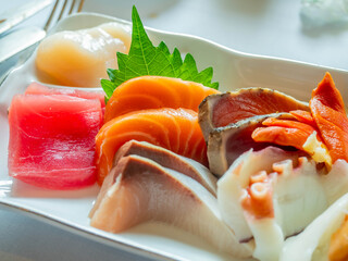 Raw seafood, sashimi, sliced on white dish in luxury restaurant, tuna, octopus, salmon, clam, scallop, squid, served in Japanese style