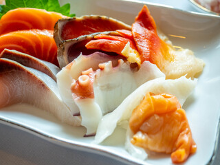 Raw seafood, sashimi, sliced on white dish in luxury restaurant, tuna, octopus, salmon, clam, scallop, squid, served in Japanese style