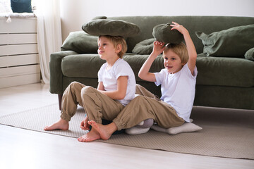kids boys have fun with pillows, sitting on the living room floor