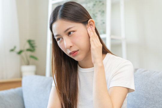 Tinnitus concept, sick asian young woman, girl have ear pain or earache, hand touch plug ear, suffering painful otitis from loud of noisy sound, inflammation. Health care nerve deaf eardrum disease.