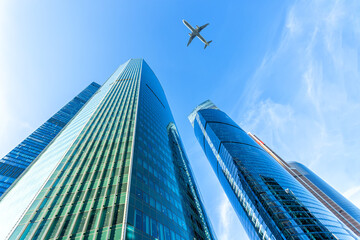 Modern glass skyscrapers on a clear day and passenger plane flies over