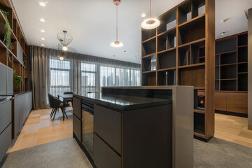 This kitchen features sleek cabinets, a large island, and a central dining area. Natural light comes through large windows. Wood and stone materials create a modern look.