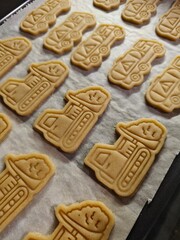 Unbaked gingerbread cookies in vehicle shapes. Raw gingerbread cookies shaped like vehicles on a baking tray before baking.