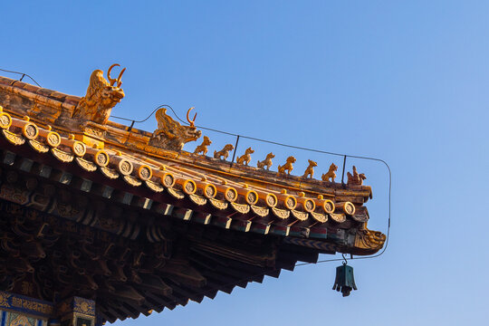 Ornate roof of Lama Temple with ceramic figures under warm light against clear blue sky showing traditional Chinese architecture, Beijing, China - Powered by Adobe