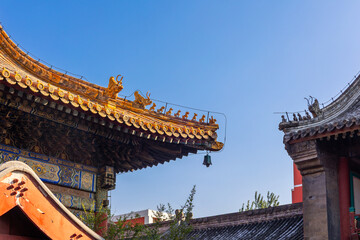 Decorative roof ridge with mythical figures and hanging bell element illustrating craftsmanship of Beijing Lama Temple, Beijing, China