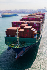 A container ship, fully loaded with goods, sails out to sea, delivering products to various locations around the world.